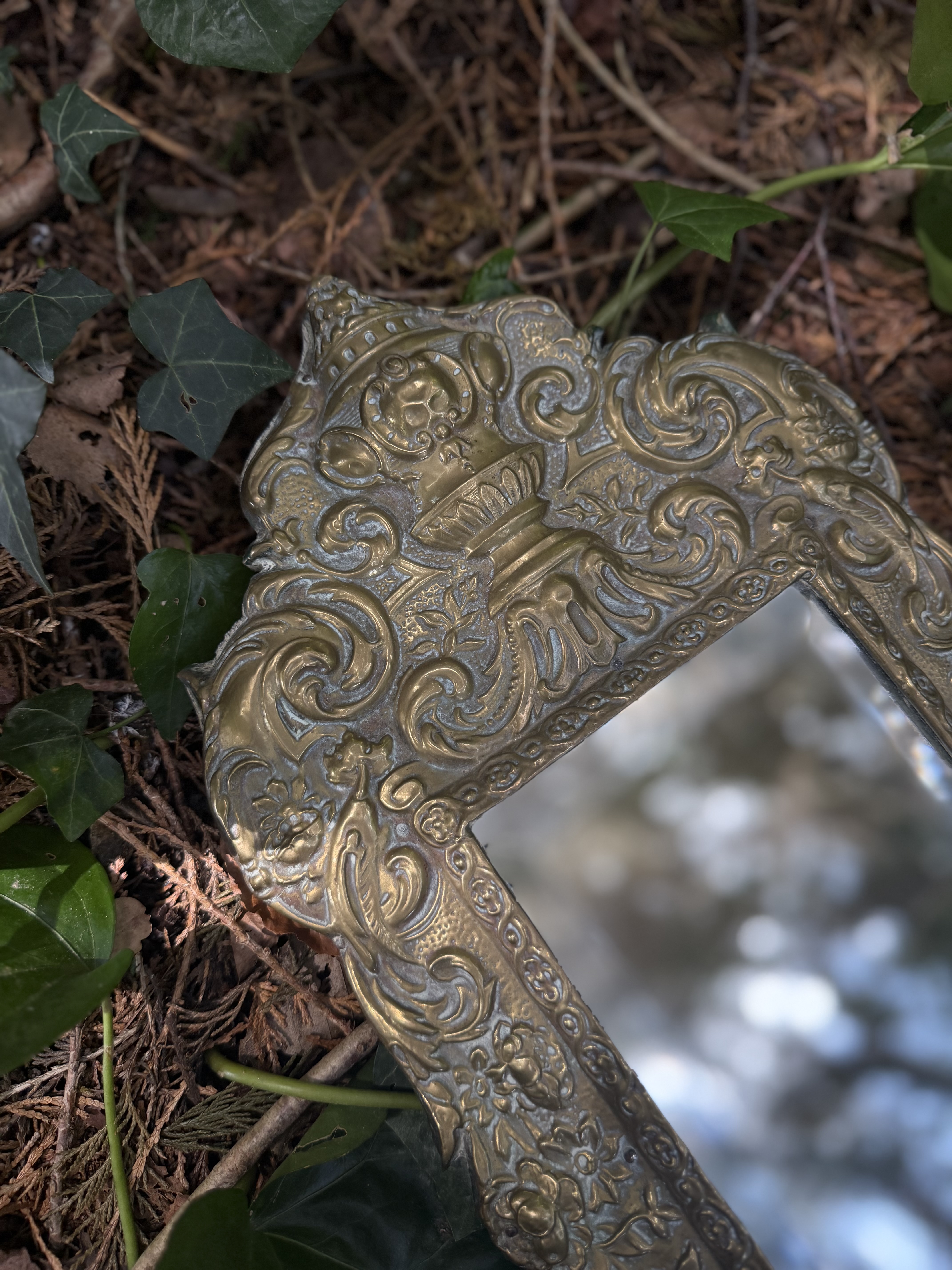 Close up of the hand stamped classical urn crest on the brass mirror