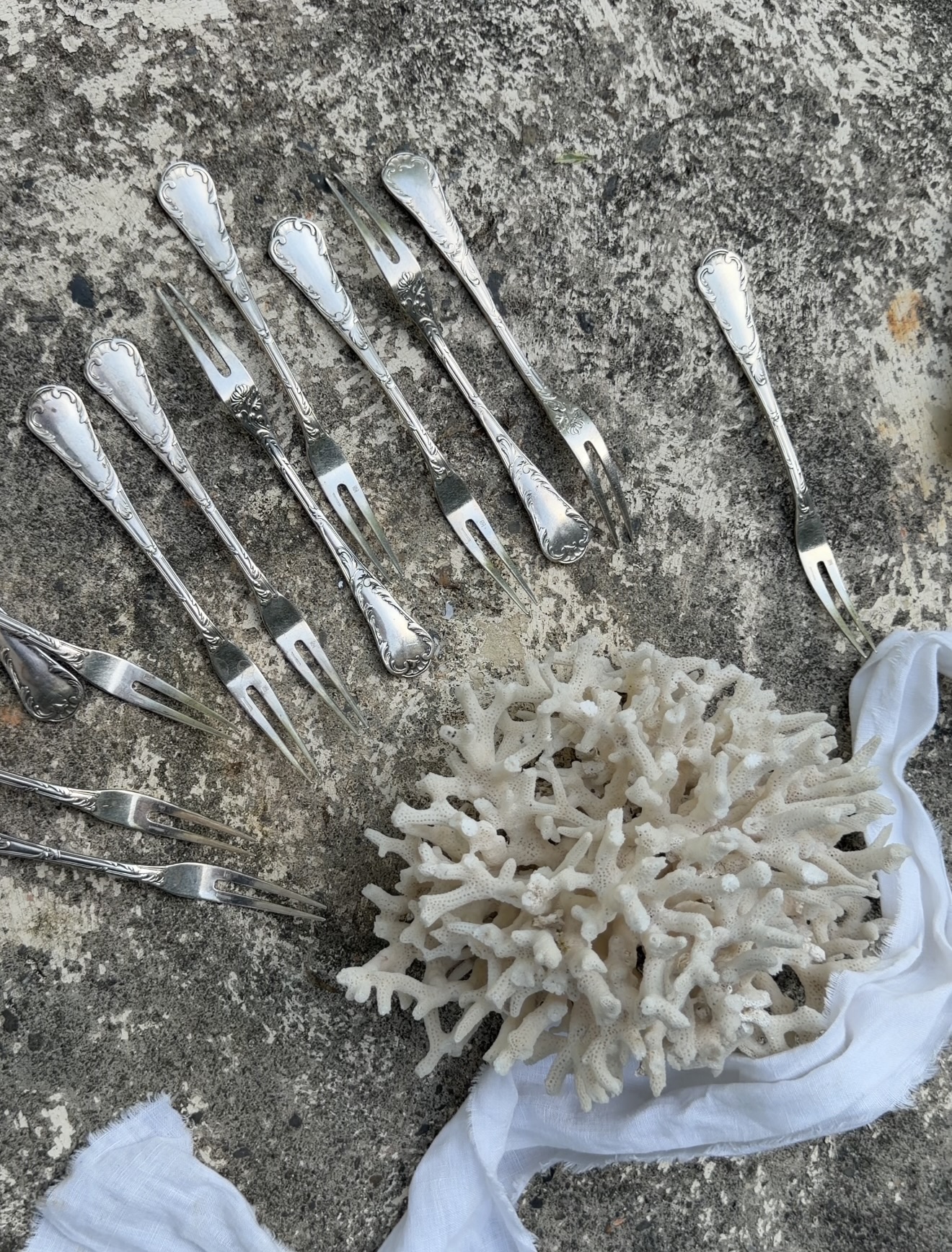 Collection of 12 antique French silver forks laid flat on a stone surface