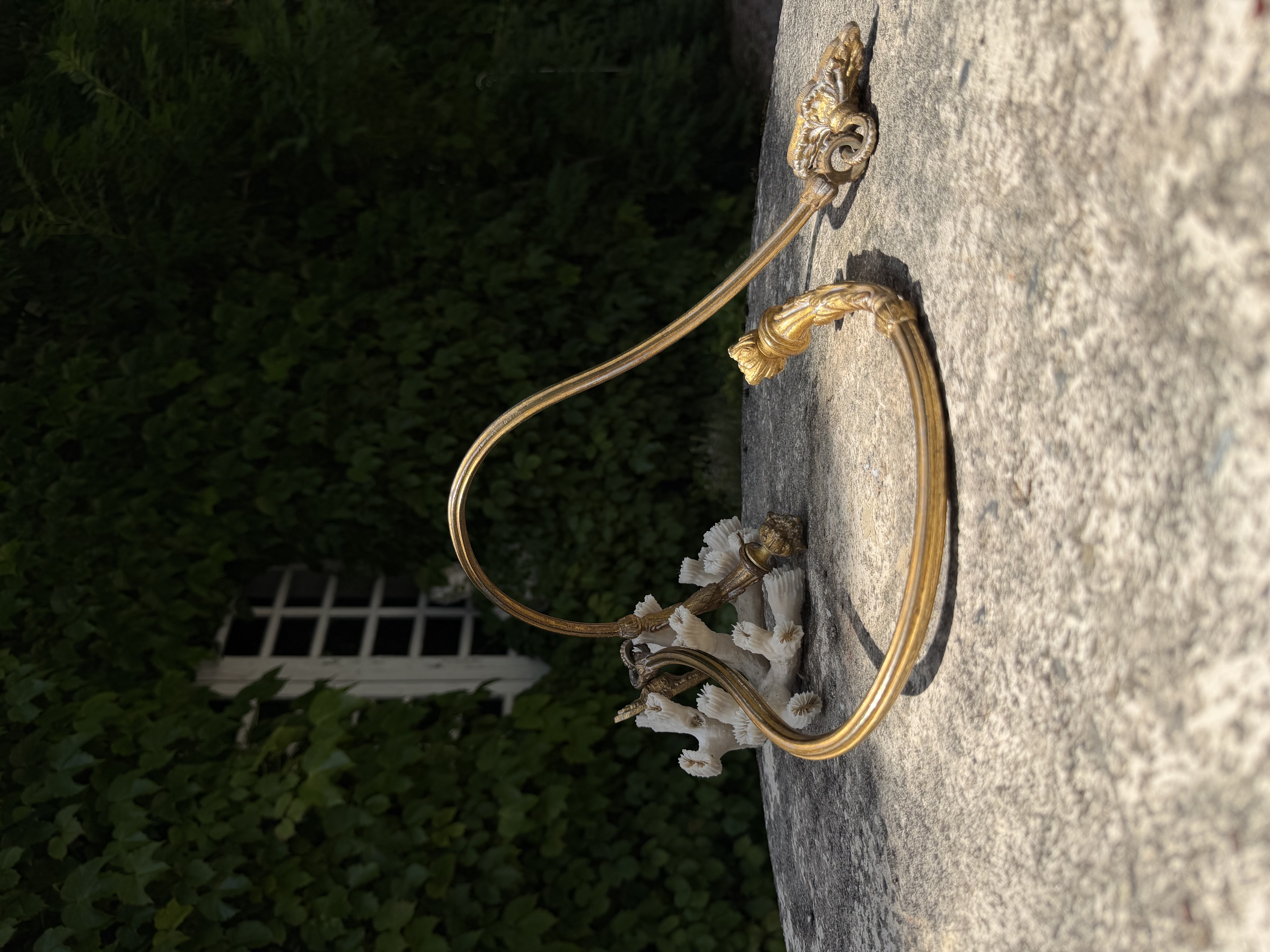 Patinated bronze curtain tie-backs resting against white coral