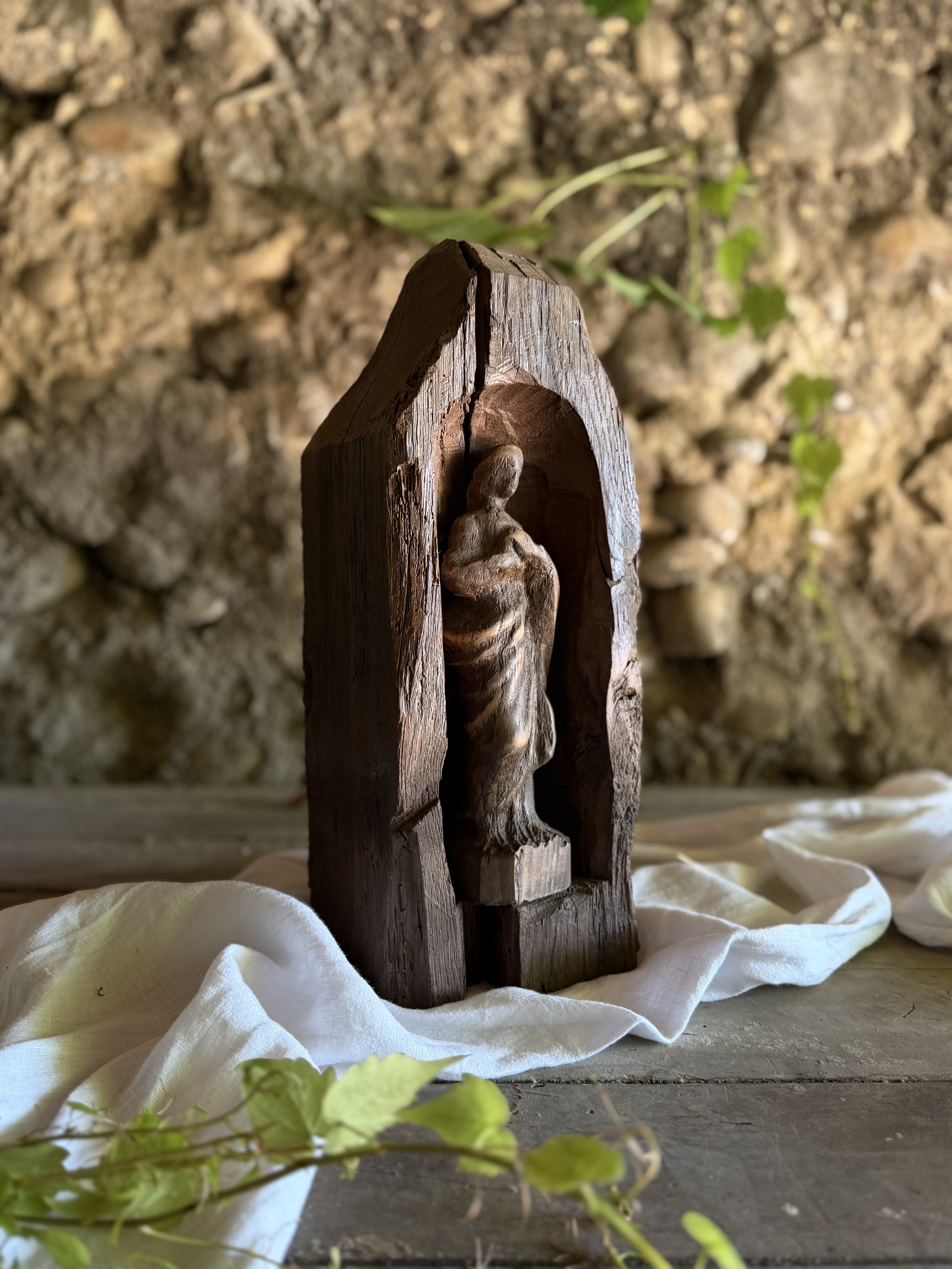 Carved wooden Madonna resting inside the shadowed architectural niche