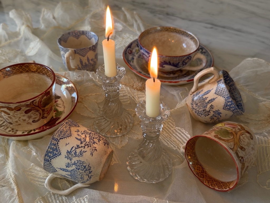 Blue and white faïence cups styled with candlelight on a marble surface