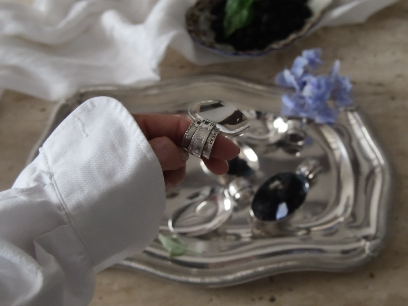 Hand holding a silver-plated tasting spoon by its unique looped ring handle