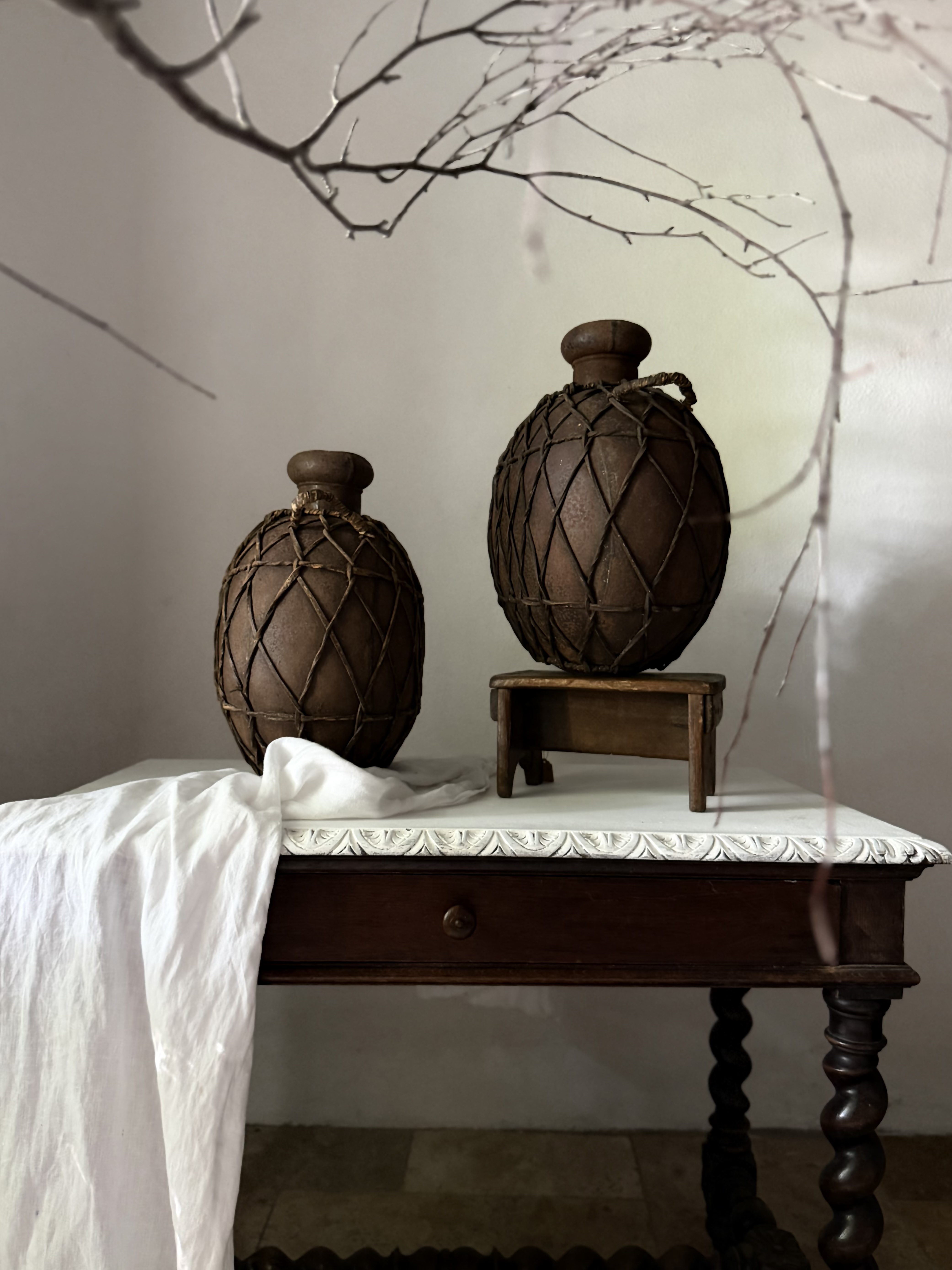 Profile view of a rustic woven metal cargo pot resting on a small stool