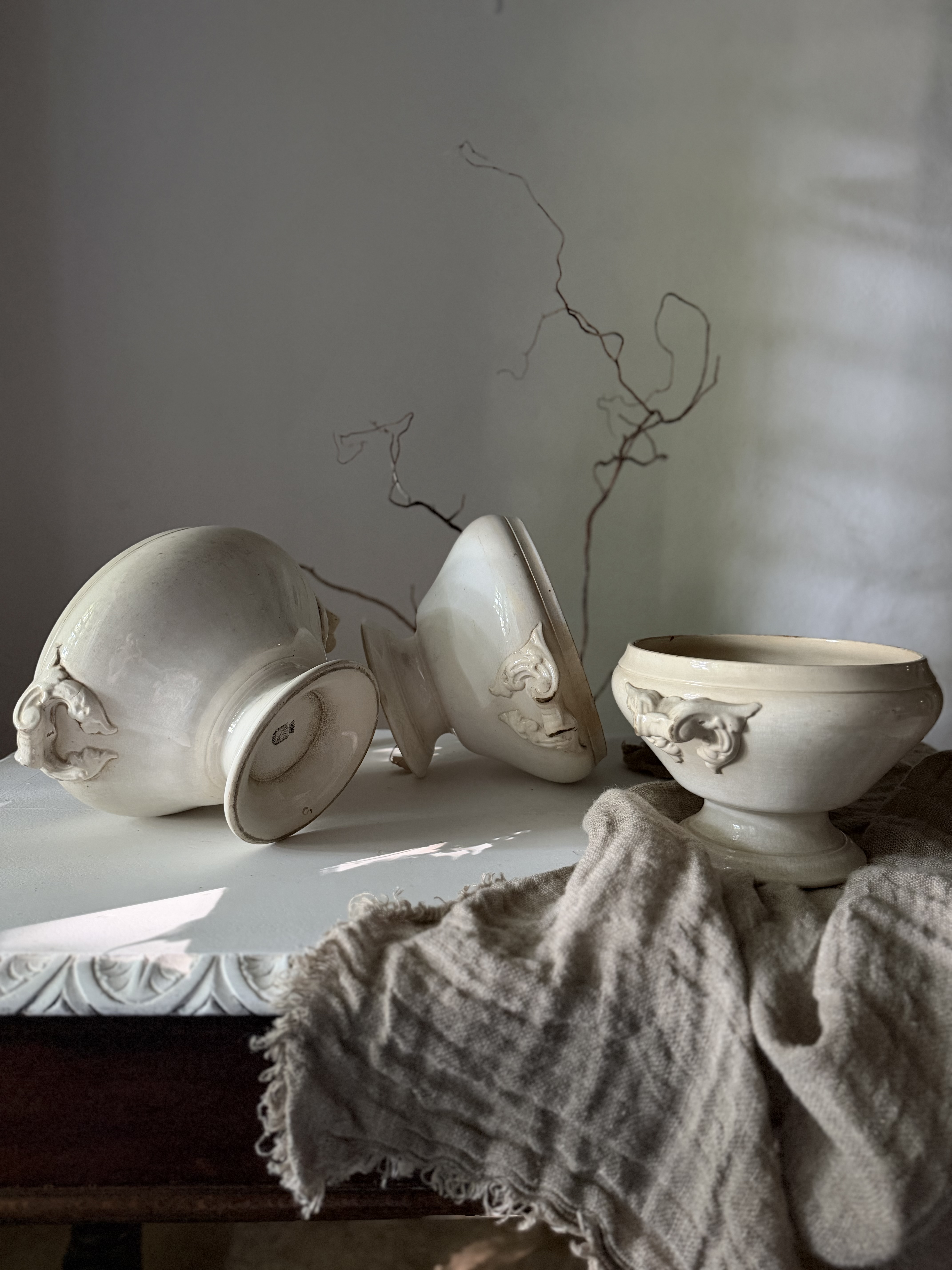 The three ironstone tureens tumbled and scattered across a wooden table