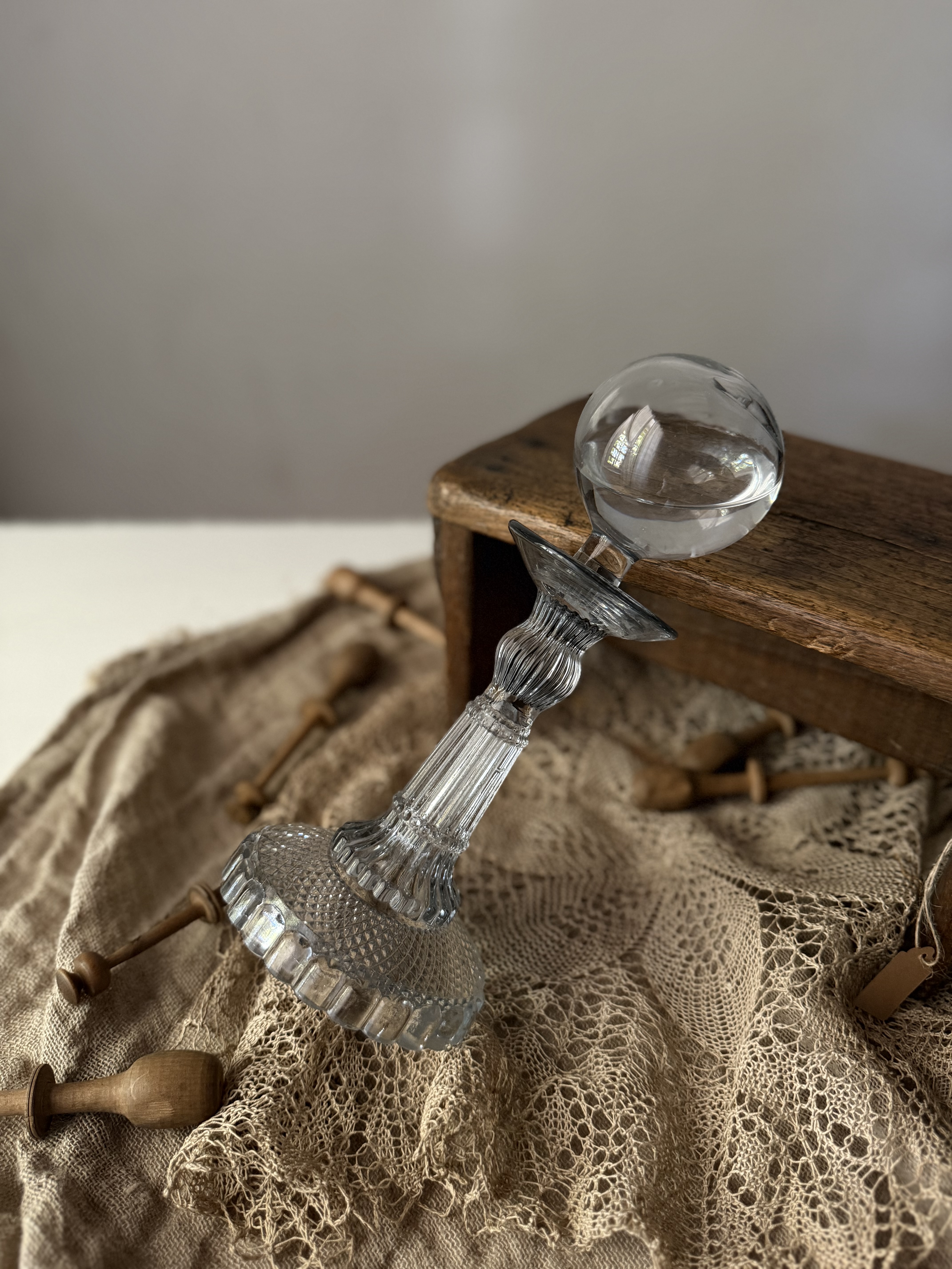 The antique glass lamp tilted against a wooden stool with antique lace